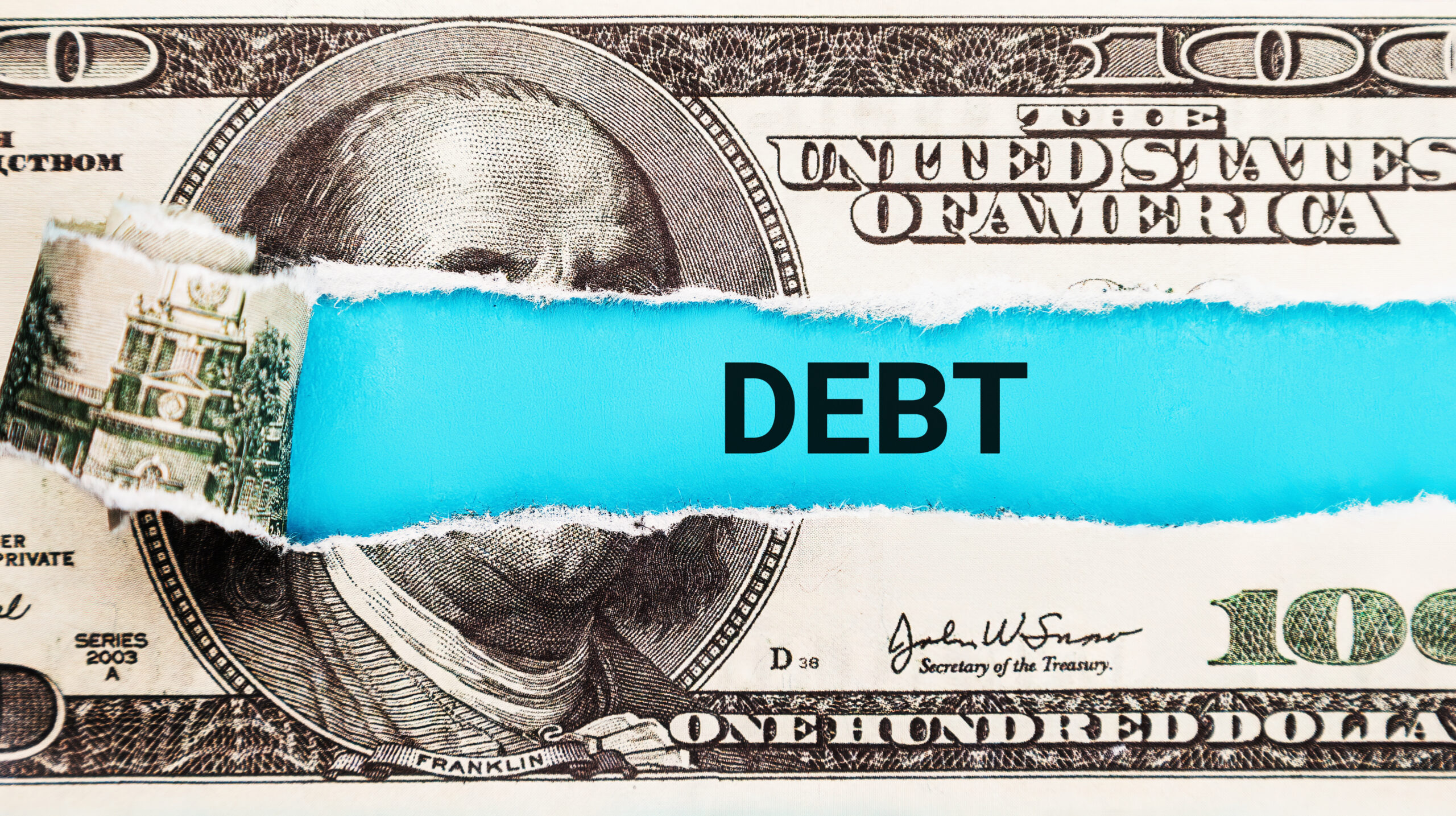 Debt. The word Debt in the background of the US dollar. Financial Burden, Loan, and Credit Concept.